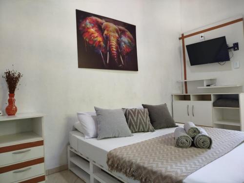 une chambre avec un lit avec un tableau sur le mur dans l'établissement Sunset Flats - Bonito Flat na Rua Pituba 1 , bem perto das praias urbanas! Itacare BA 2, à Itacaré