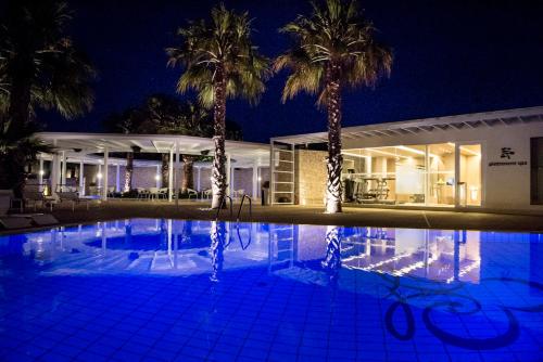 a swimming pool in front of a house with palm trees at Pietre Nere Resort & Spa in Modica