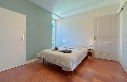 a white bedroom with a bed and a window at Du soleil au balcon - Hypercentre in Lons-le-Saunier