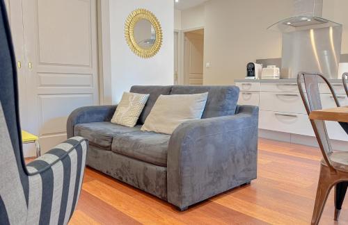 a living room with a couch and a chair at Du soleil au balcon - Hypercentre in Lons-le-Saunier