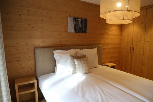 - une chambre avec un lit blanc et un mur en bois dans l'établissement Dent Blanche Resort - TemptingPlaces Collection, à Hérémence