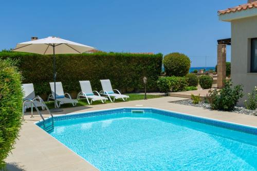 a swimming pool with chairs and an umbrella at Seaview Villa Mia in Lachi