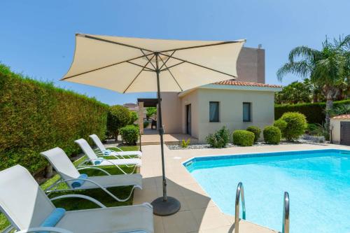 a pool with chairs and an umbrella next to a house at Seaview Villa Mia in Lachi