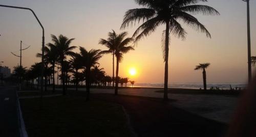 eine Gruppe von Palmen am Strand mit Sonnenuntergang in der Unterkunft Lar do Litoral - Praia Grande in Praia Grande