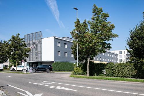 a building with a car parked in front of a street at Hotel Arte Spreitenbach in Spreitenbach