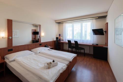 a bedroom with a large bed and a desk with chairs at Hotel Arte Spreitenbach in Spreitenbach