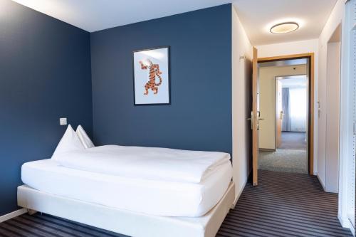um quarto com uma grande cama branca numa parede azul em Self Check-In Hotel David 22 em St. Gallen