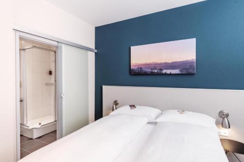 a bedroom with a white bed and a blue wall at Sorell Hotel Rex Zürich in Zürich