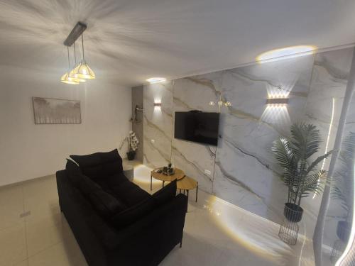 a living room with a couch and a tv on a wall at פינוק של סוויטה in Manot