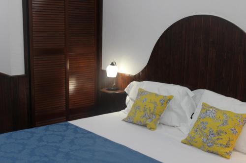 a bedroom with a bed with yellow and blue pillows at Cascais Jasmim Doce in Cascais