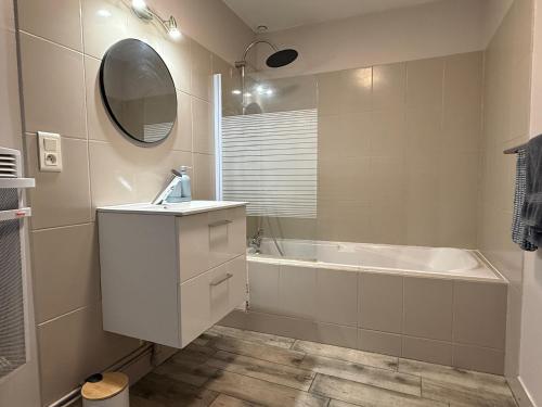 a bathroom with a sink and a tub and a mirror at Trois pièces vue campagne à Bâlines in Balines