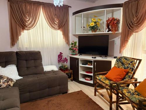 a living room with a couch and a flat screen tv at Omma's Haus - Casa de Vó perto de Gramado in Morro Reuter