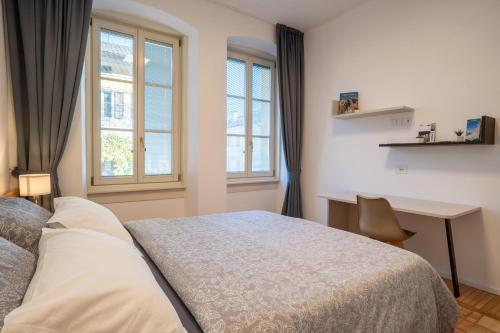 ein Schlafzimmer mit einem Bett, einem Schreibtisch und Fenstern in der Unterkunft Apartments and holidays Cav Paolo Tione di Trento in Tione di Trento