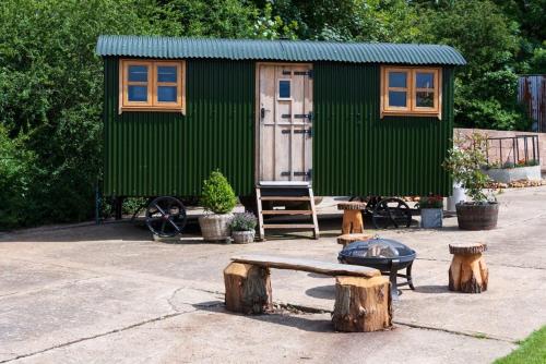 a green tiny house with a bench and logs at Shepherds hut in Kent