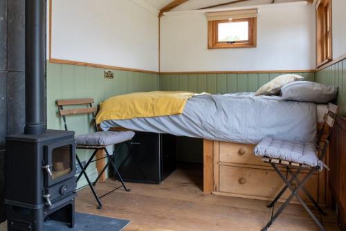 a bed in a room with a wood stove at Shepherds hut in Kent
