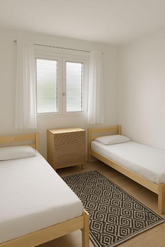 two beds in a room with two windows and a rug at Villa Valey, spacious and authentic in Le Lamentin