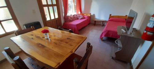 a room with a wooden table and a bedroom at Las Rosas EH in El Hoyo