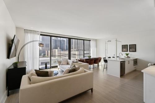 a living room with white furniture and a large window at The Theodore New Orleans in New Orleans
