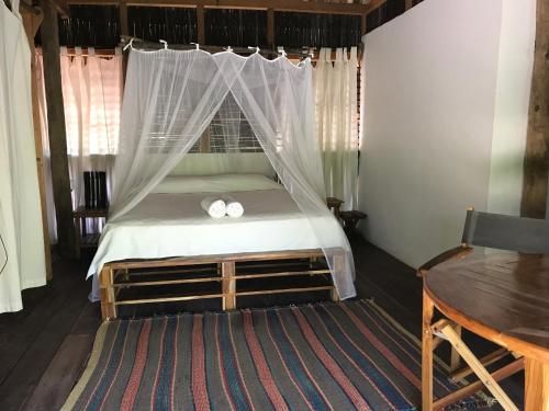 a bedroom with a bed with two white towels on it at Playa Pikua Ecolodge in Guachaca