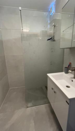 a white bathroom with a shower and a sink at MiMi in Brussels