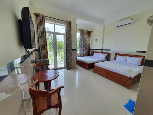a bedroom with two beds and a table and a television at Motel Bờ Kè in Bà Rịa