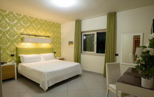 カターニアにある4 スパ リゾート ホテルのベッドルーム1室(白いベッド1台、デスク、窓付)