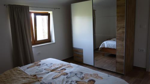ein Schlafzimmer mit einem Spiegel, einem Bett und einem Fenster in der Unterkunft Apartma Pergola in Sečovlje