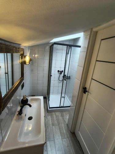 a white bathroom with a sink and a shower at Nad Dachami Poznania - apartament nr 7 in Poznań