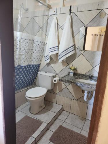 a bathroom with a toilet and a sink and towels at Villa Mediterraneo in Beberibe