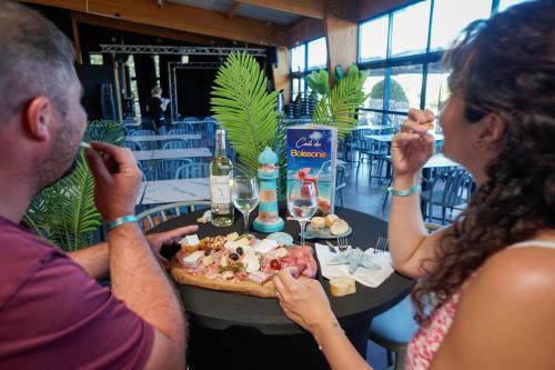 Camping Saint Georges d'Oléron في سا جورج دوليه: مجموعة من الناس يجلسون على طاولة يأكلون البيتزا