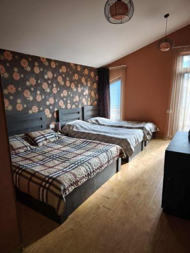 two beds in a bedroom with floral wallpaper at Cottage Sunny Side in Bakuriani