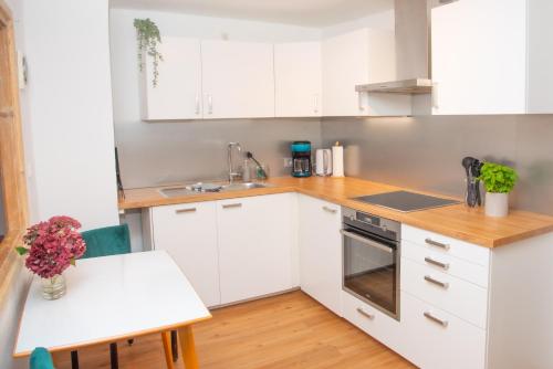 a kitchen with white cabinets and a table with flowers at Gemütlich gestaltetes, familiengeführtes Apartment mit Burgblick in Burghausen