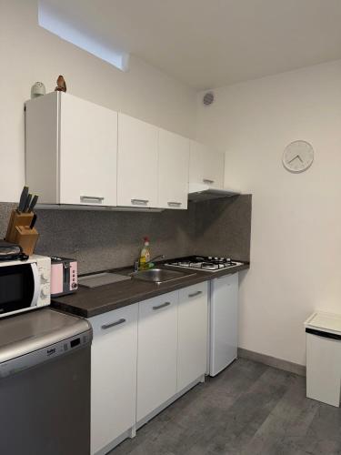 Una cocina con gabinetes blancos, un fregadero y un microondas. en Útulný byt v blízkosti centra, en Juliánov