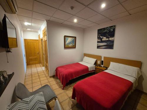 ein Hotelzimmer mit 2 Betten mit roter Bettwäsche in der Unterkunft Hotel Bon Lloc in Ulldecona