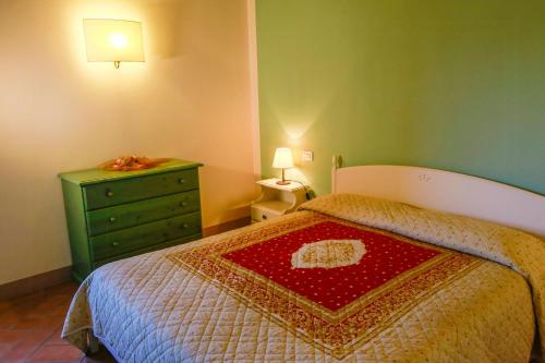 une chambre avec un lit et une commode verte avec une couverture rouge dans l'établissement Historic Farmhouse Overlooking San Gimignano, à San Gimignano
