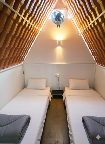 two beds in a small room with a ceiling at Beer Hostel Ilhabela in Ilhabela
