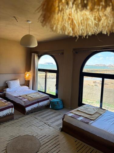 a bedroom with two beds and two large windows at Wazidi Resort in Siwa