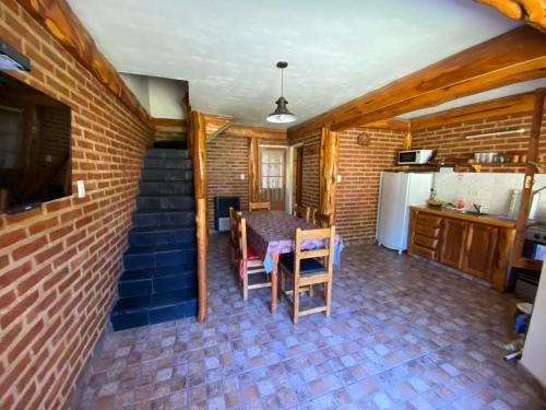 a kitchen and dining room with a table and a brick wall at Dúplex Las Malvinas in El Bolsón