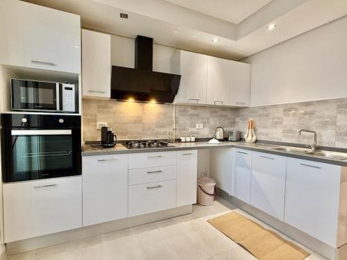 a kitchen with white cabinets and a stove top oven at Residence The Green in Tunis