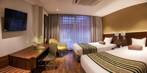 a hotel room with two beds and a desk at Hotel Rennova in La Paz