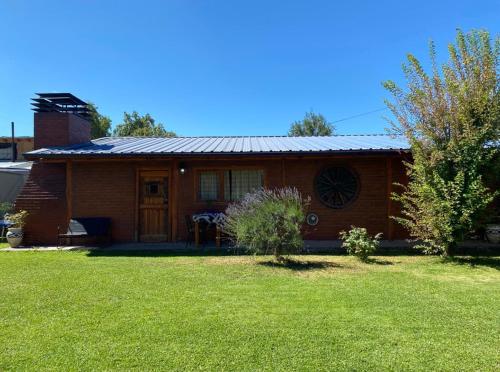 a small house with a grass yard in front of it at Dúplex Las Malvinas in El Bolsón