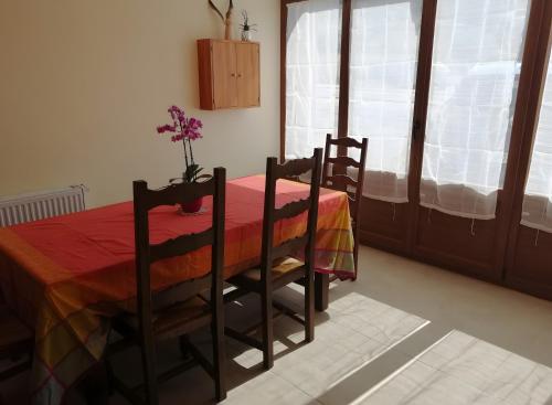 勒帕勒Maison D'hôtes Les Brimbelles的一张桌子,两把椅子,花瓶上放着鲜花