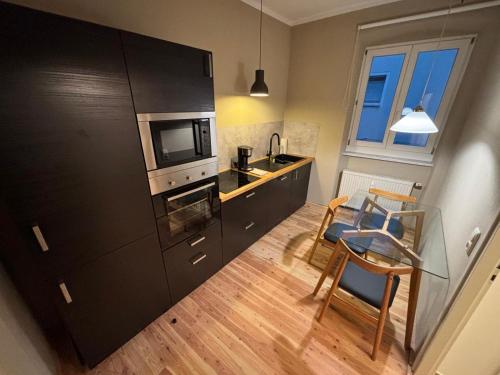 eine Küche mit einem schwarzen Kühlschrank sowie einem Tisch und Stühlen in der Unterkunft Cityappartment am Regensburger Dom in Regensburg