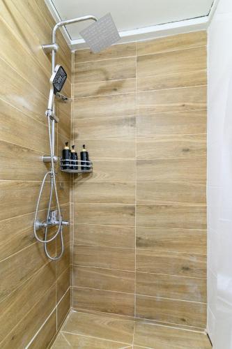 a bathroom with a shower with a wooden wall at Studio 35 - Modern & Cozy Studio in Chalandri City Center in Athens