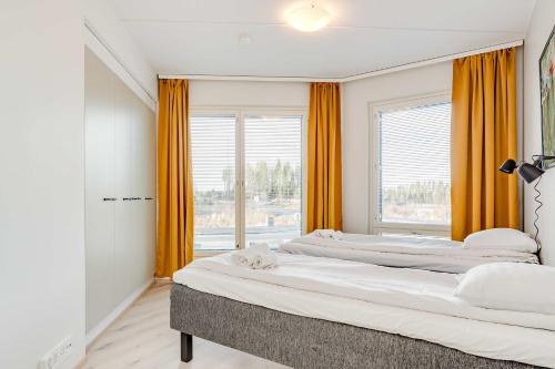 two beds in a room with orange curtains at Hiisi Homes Kangasala in Suorama