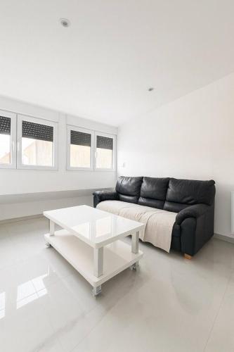 ein Wohnzimmer mit einer schwarzen Couch und einem Tisch in der Unterkunft DeLuxe Studio Lumineux, Rénové, Parking Gratuit, MULHOUSE CENTRE in Mulhouse