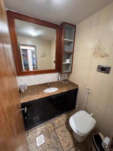 a bathroom with a toilet and a sink and a mirror at PERÓ BEIRA MAR - Flat âncora - 203A in Cabo Frio