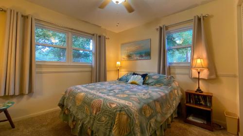 a bedroom with a bed and two windows at Island Pines in Jekyll Island