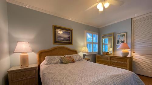 a bedroom with a bed and two lamps and windows at Hollybourne II in Jekyll Island