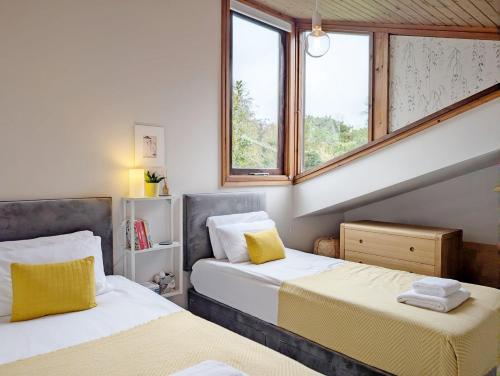 Dos camas en una habitación con dos ventanas. en The Nest at Severels, en North Mundham